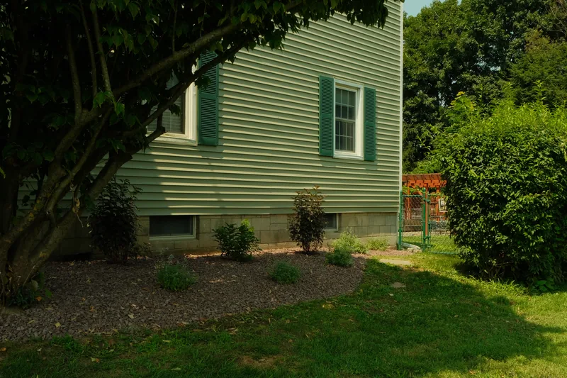Young shrubs in a dark stone mulch bed along a house foundation